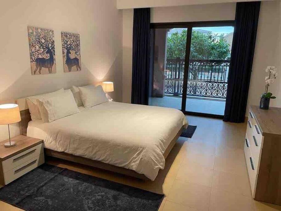 a bedroom with a large bed and a balcony at Three bedroom apartment in Saadiyat district in Abu Dhabi