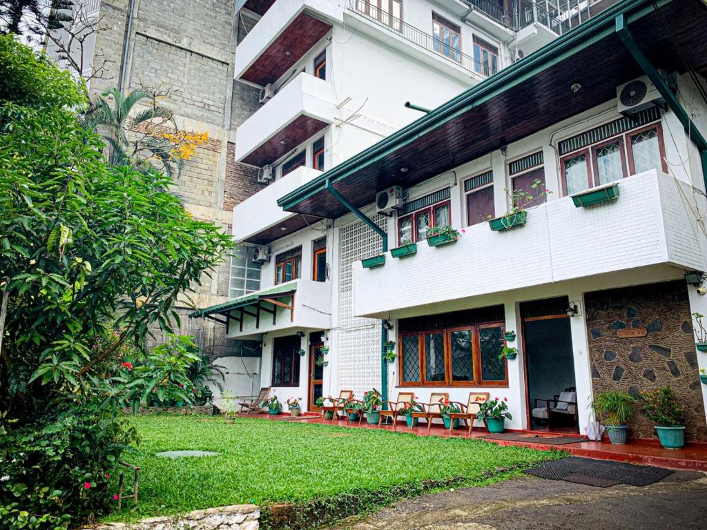 un bâtiment blanc avec une pelouse devant lui dans l'établissement Sharon Inn, à Kandy
