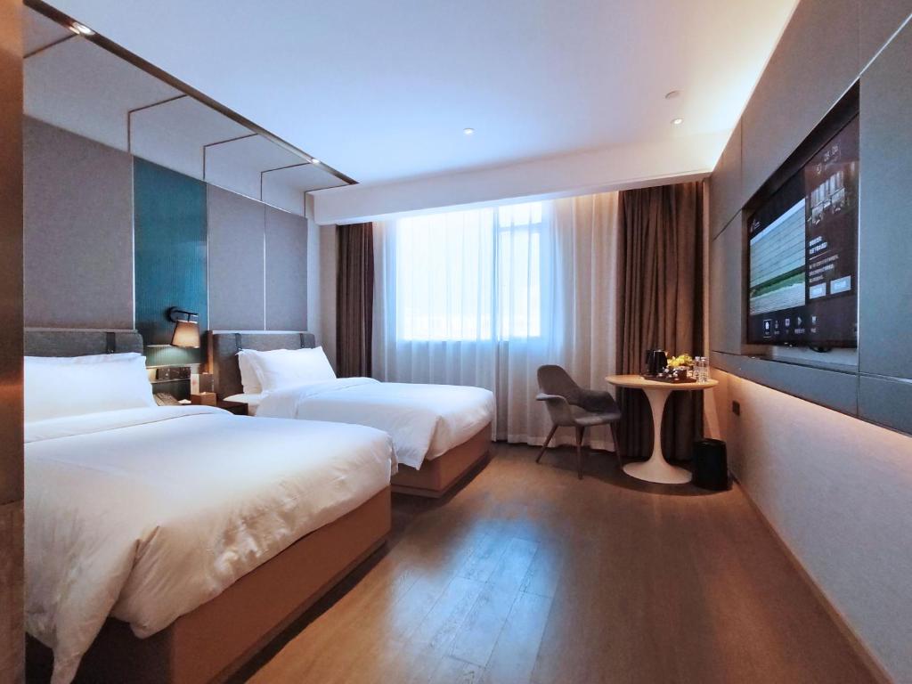 Paco Hotel Guangzhou South Railway Station Panyu Changlong Branch في قوانغتشو: غرفه فندقيه سريرين وتلفزيون