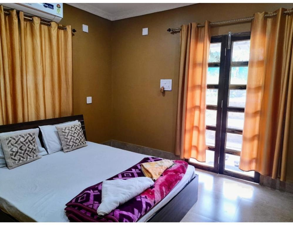 a bedroom with a bed and a large window at Similipal Eco Retreat, Jaybilla, Odisha in Bālidiha