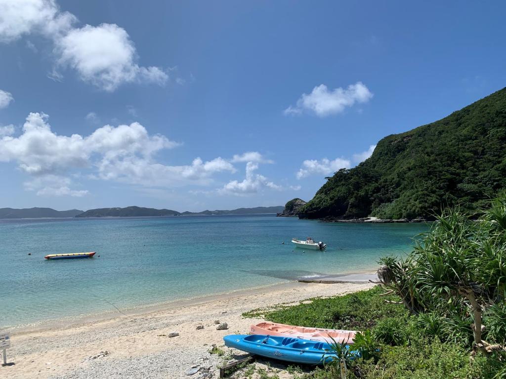 a beach with two boats in the water at HOTEL KANALOA in Tokashiki