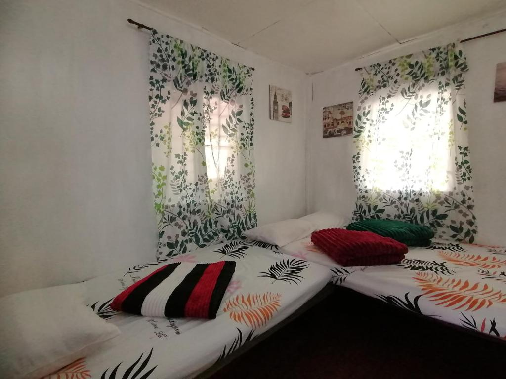 two beds in a room with two windows at BATAD CRISTINA'S Main Village INN & Restaurant in Banaue