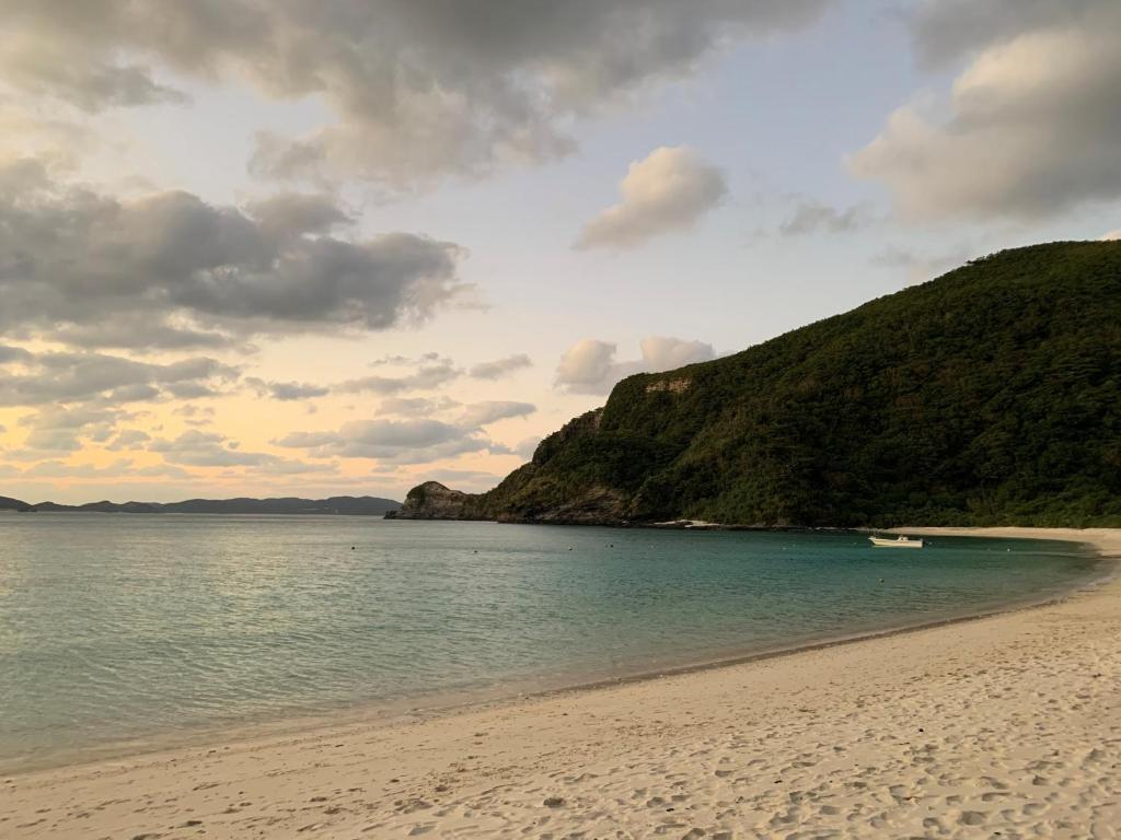 a beach with a boat in the water at HOTEL KANALOA in Tokashiki