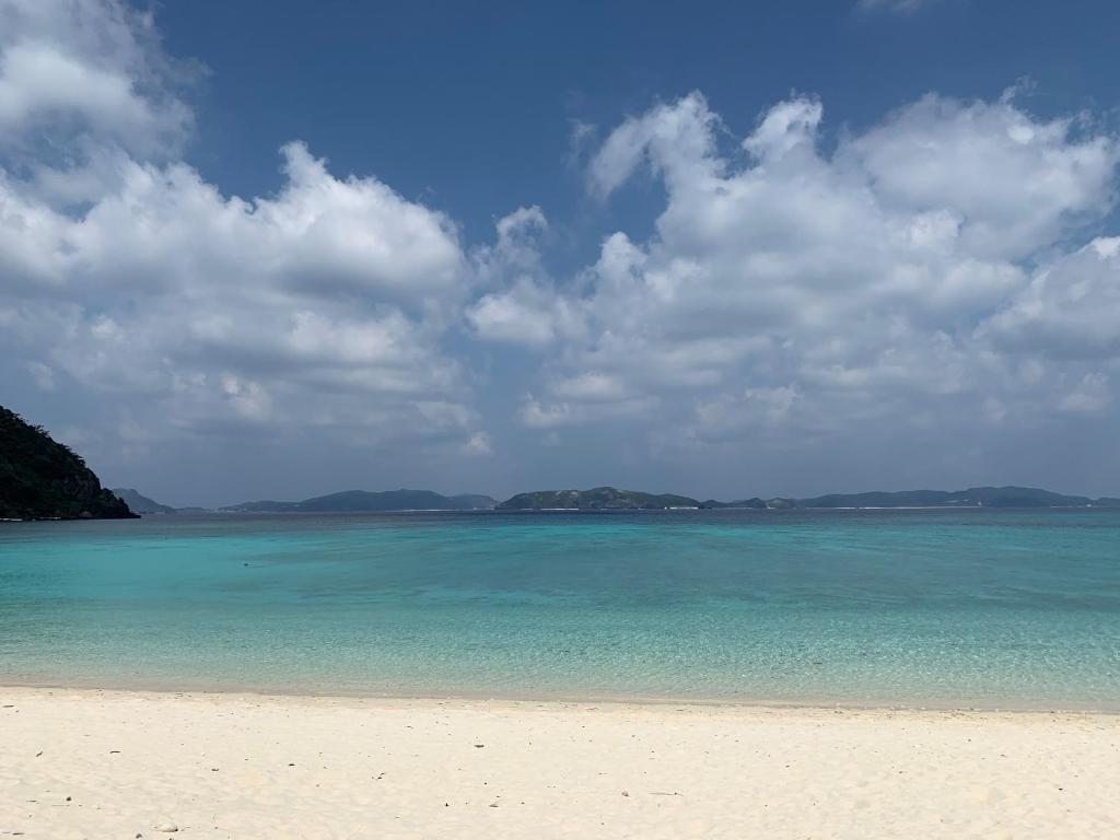 a beach with blue water and clouds in the sky at HOTEL KANALOA in Tokashiki