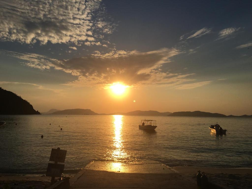 a sunset over a body of water with boats at HOTEL KANALOA in Tokashiki