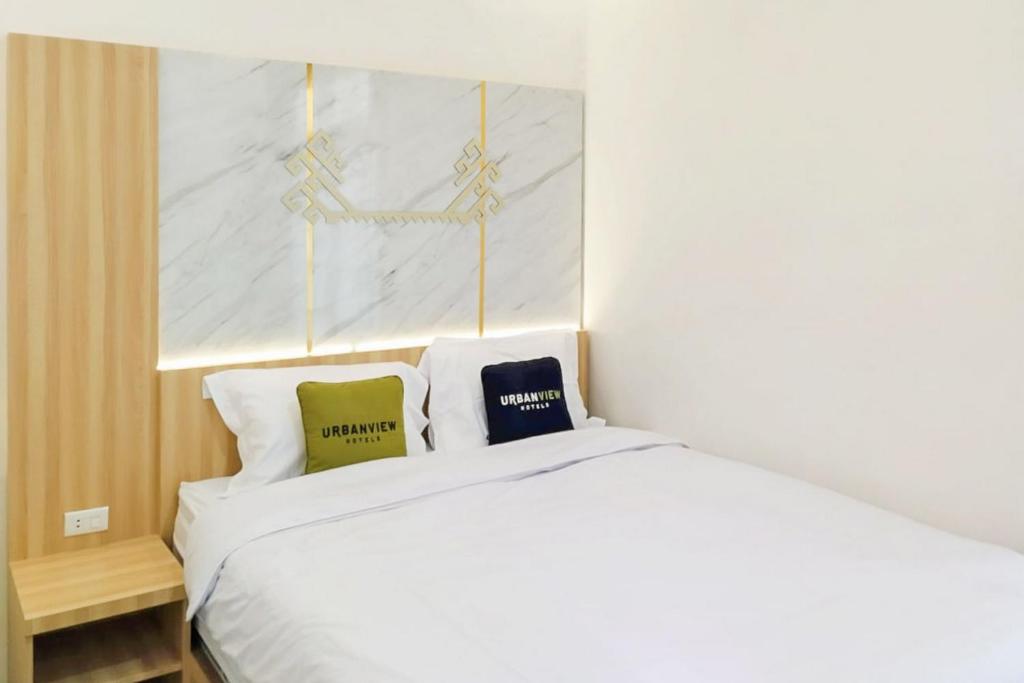 ein weißes Bett mit zwei Kissen darüber in der Unterkunft Urbanview Hotel Tritia Lampung in Kedaton