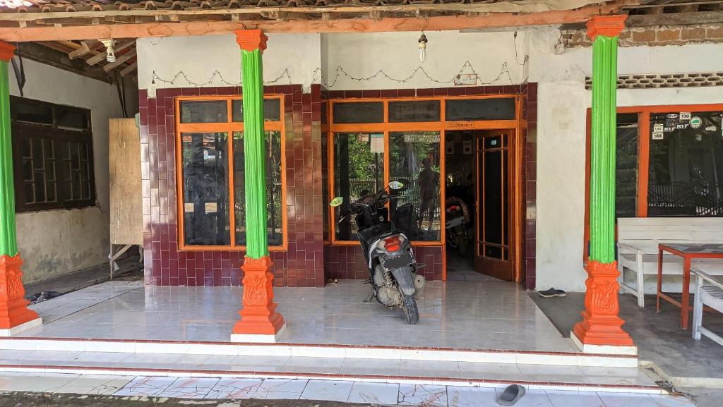 ein Motorrad, das vor einem Gebäude mit grünen Säulen parkt in der Unterkunft Kostel Al-Barokah 