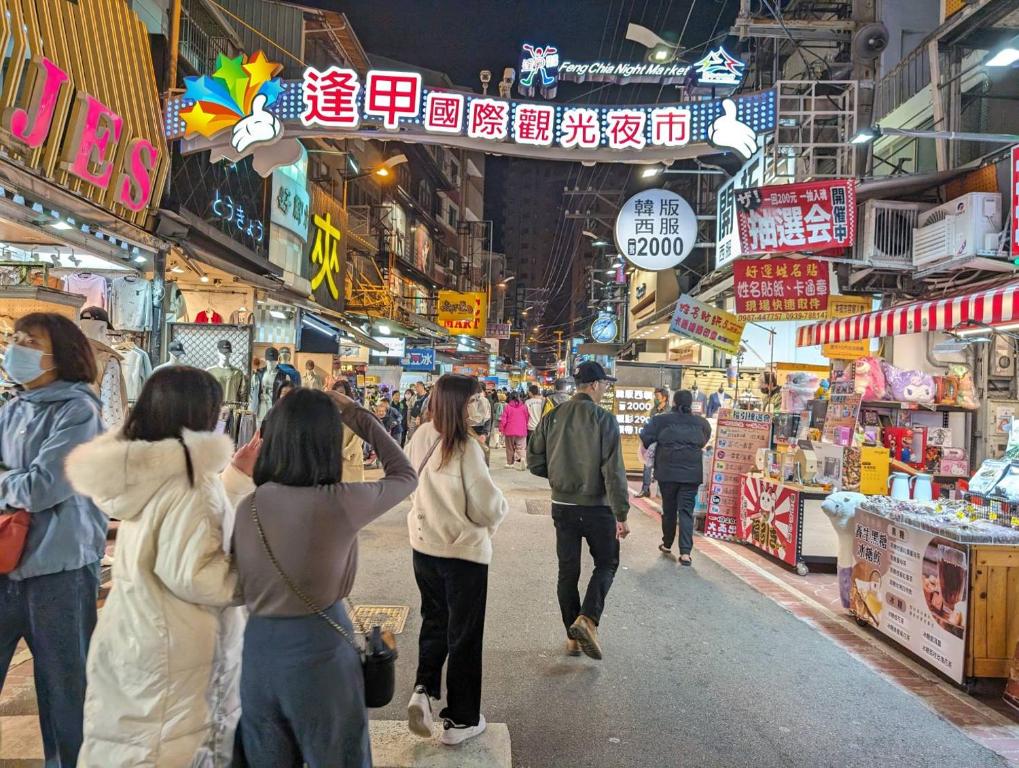 a group of people walking down a street in a market at In One City Inn in Taichung