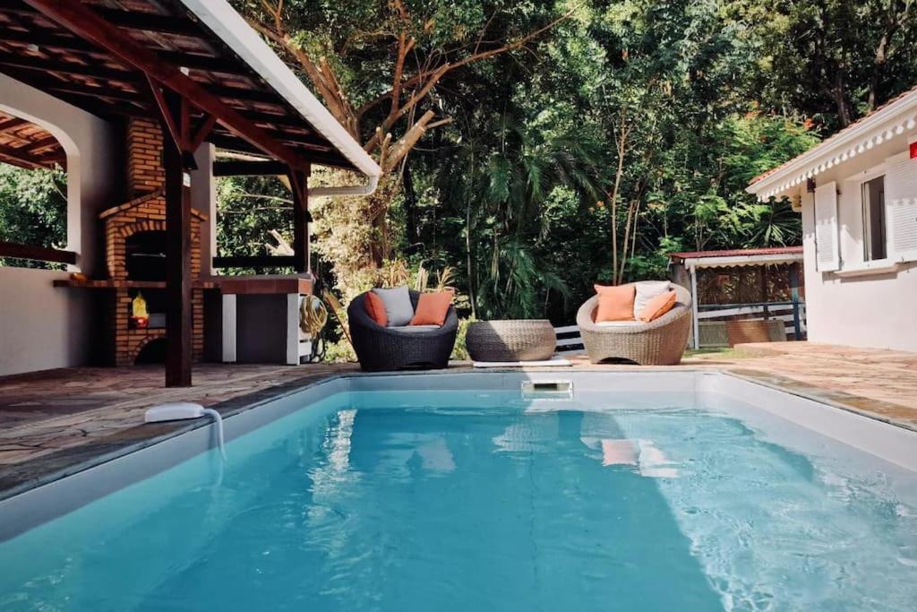 een zwembad in een achtertuin met 2 stoelen bij Villa Mahogany confort, spacieuse in Le François