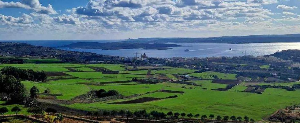 an aerial view of a green field with a lake at Twenty9th in Nadur
