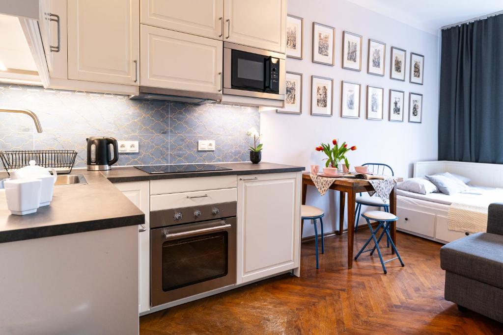 a kitchen with white cabinets and a living room at Cozy Old Town Studio in Krakow