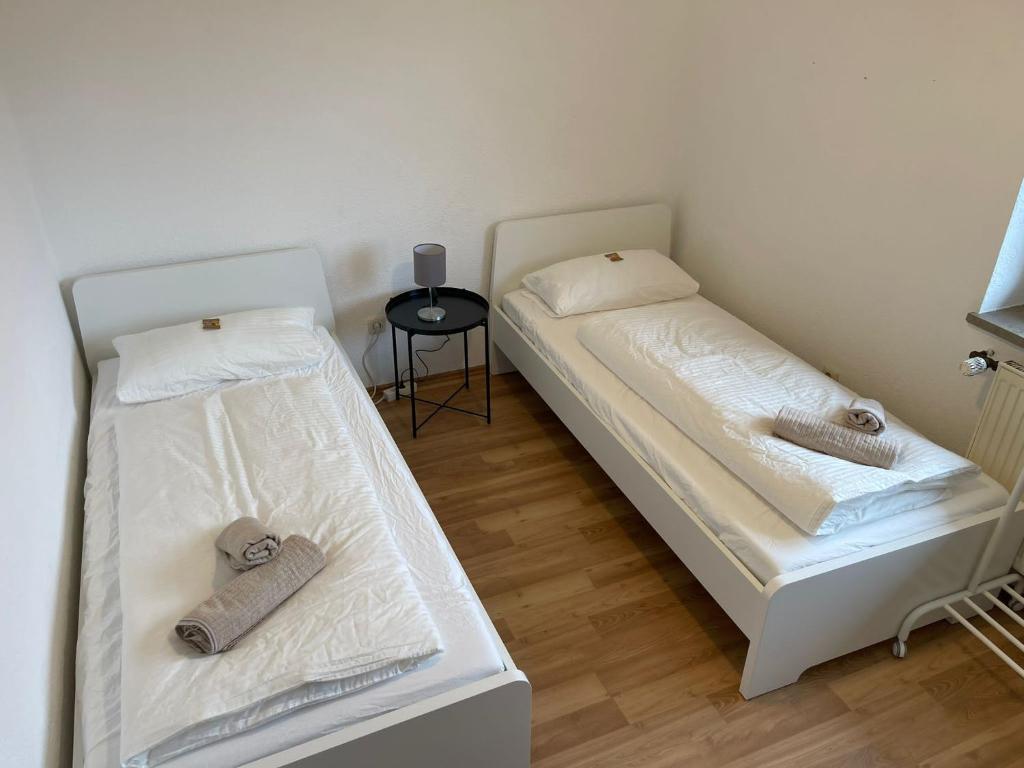 Duas camas num pequeno quarto com uma mesa em Bavaria Home - Küche, Terrasse, 3 Schlafzimmer em Mainburg