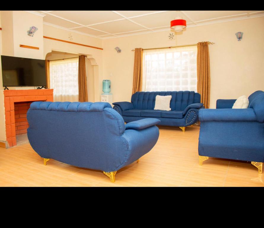a living room with blue couches and a television at Airport View Homes in Eldoret