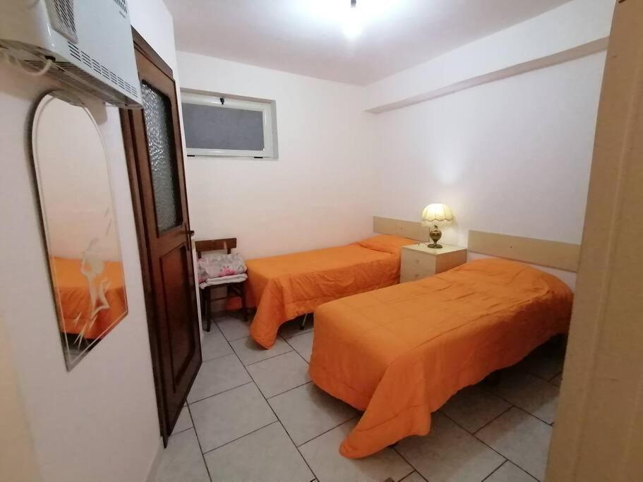 twee bedden in een kamer met oranje lakens bij Monolocale 3 letti con cucina e parcheggio gratuito in Candela