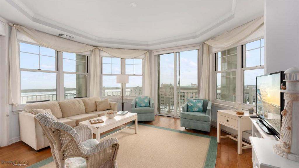a living room with a couch and chairs and windows at Residence 703 At The Grand in Wildwood