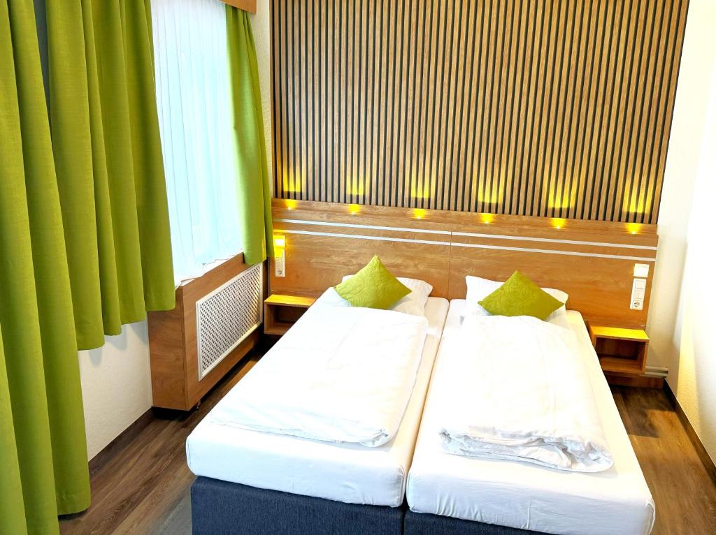 2 camas en una habitación con cortinas verdes en Berghotel Glockenberg, en Sankt Andreasberg