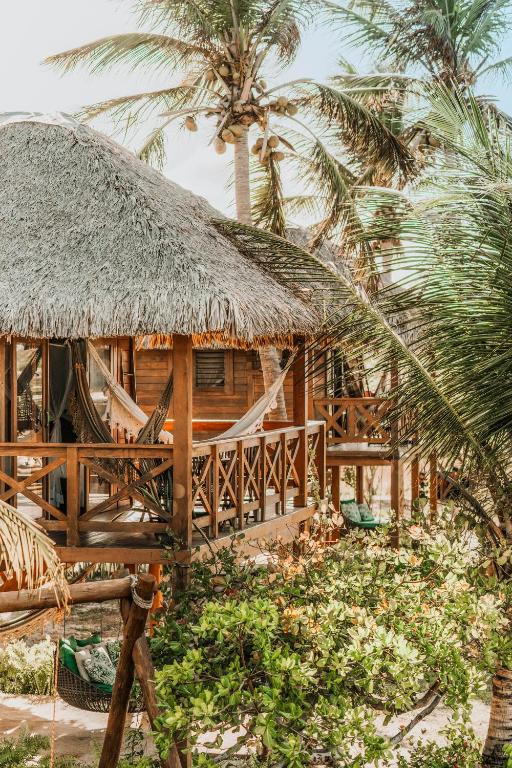 a resort with a hammock and palm trees at Vila Vento in Atins
