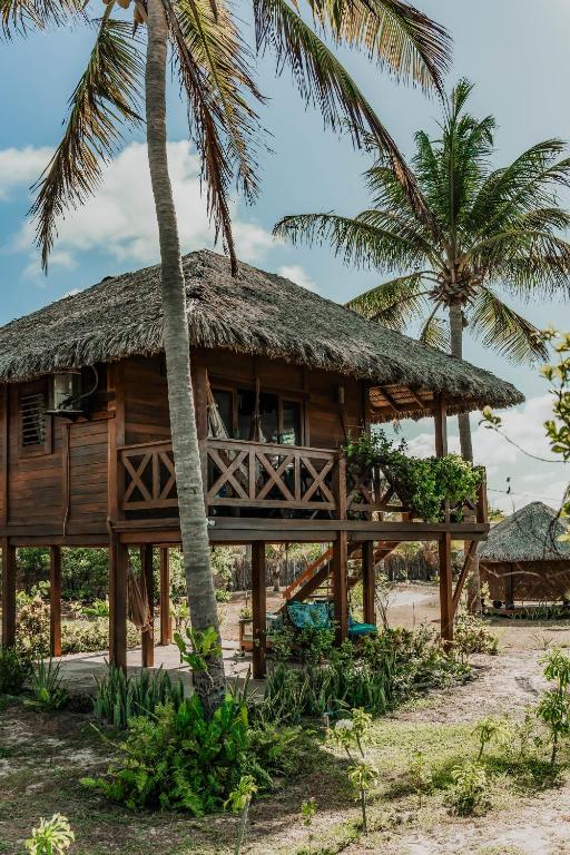 a wooden house on the beach with palm trees at Vila Vento in Atins