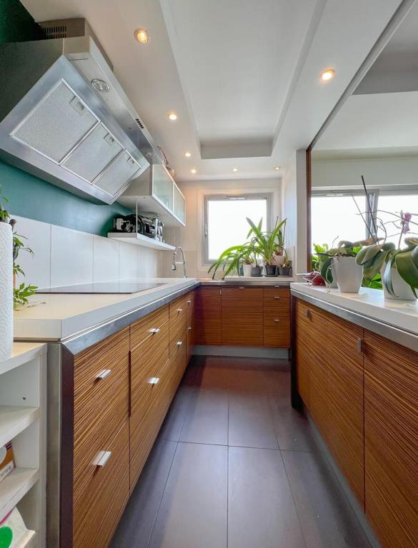 a large kitchen with wooden cabinets and a window at Full apt - Top floor - Eiffel Tower Panoramic View in Issy-les-Moulineaux