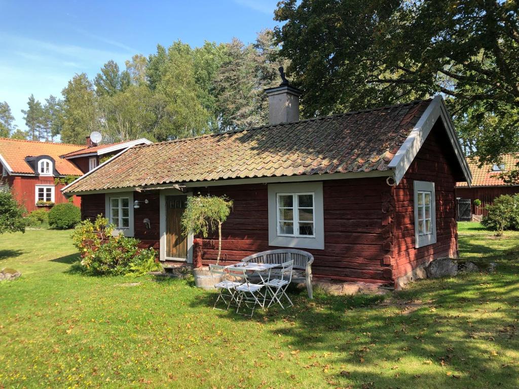 una pequeña casa con una mesa en el patio en Stuga från 1600 talet, 17th century cottage en Eskilstuna