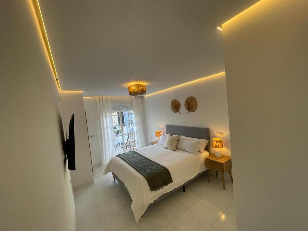 ein weißes Schlafzimmer mit einem Bett und einem Fenster in der Unterkunft La Cala Beach Home in La Cala del Moral