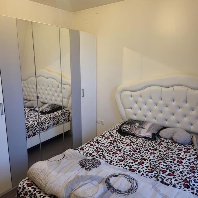 - une chambre avec un lit et un miroir dans l'établissement Appartement proche de Paris nord -Stade de France -Adidas Arena- Montmartre, à Deuil-la-Barre