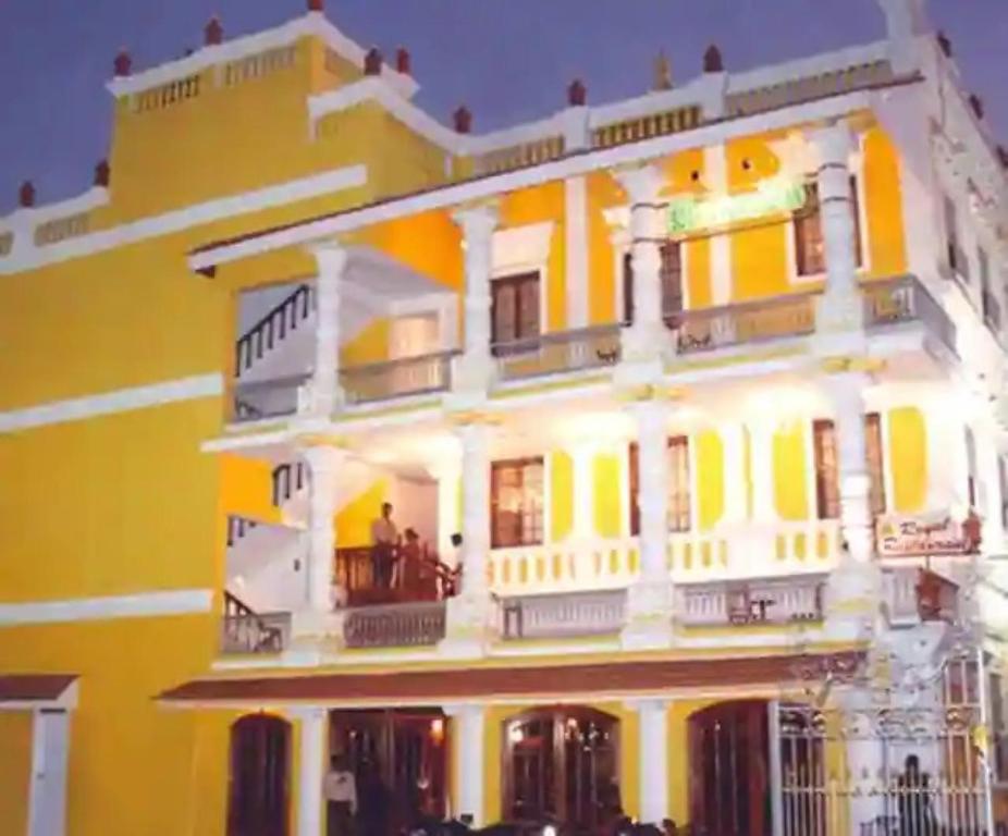 a large yellow building with people on a balcony at Hotel Soorya Inn in Puducherry
