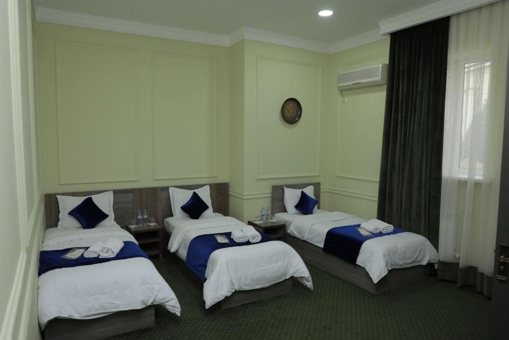 a hotel room with three beds and a window at OA Tashkent in Qŭyliq