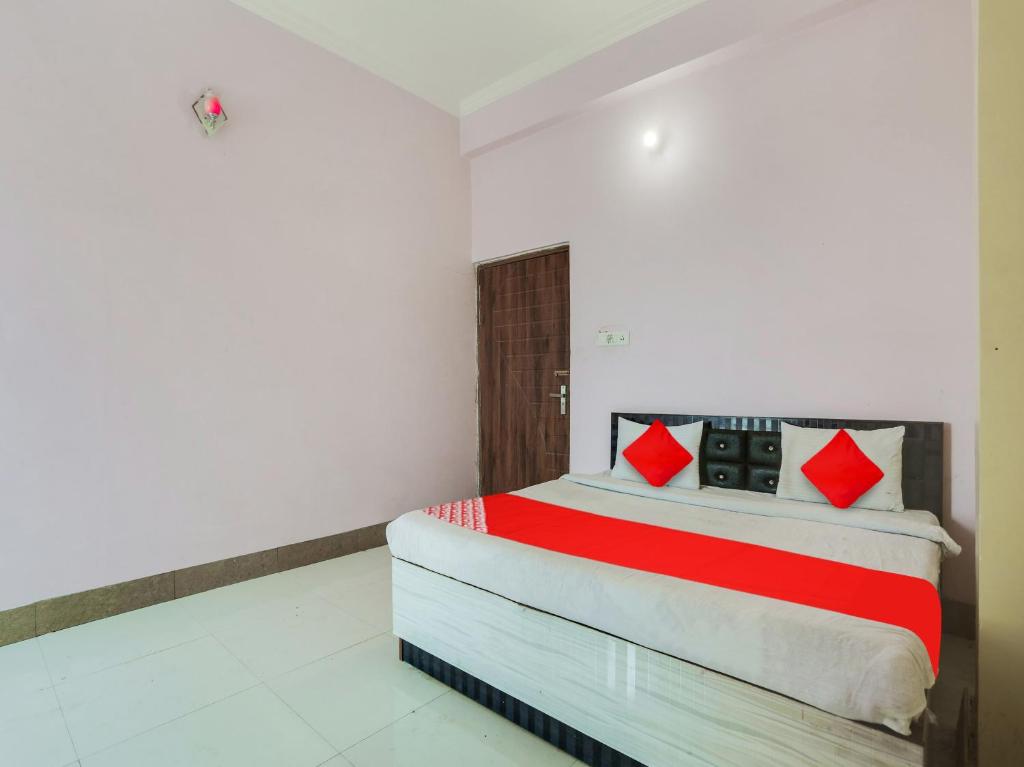 ein Schlafzimmer mit einem Bett mit roten Kissen darauf in der Unterkunft OYO Flagship Radhe Radhe Hotels in Kānpur