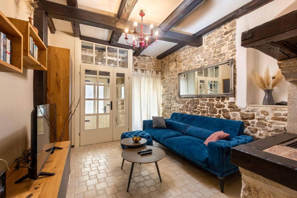 - un salon avec un canapé bleu et un mur en pierre dans l'établissement Rustic holiday house with jacuzzi, 4 Seasons, à Pazin