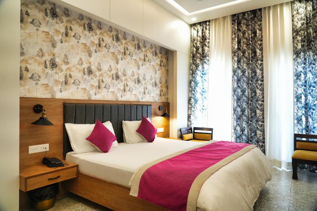 um quarto com uma cama grande e almofadas cor-de-rosa em HOTEL GRP INN CITY HOME em Pithorāgarh