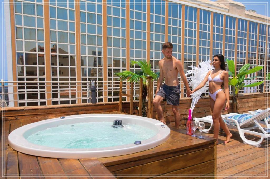a man and a woman standing next to a hot tub at Dream Beach Hotel And Spa in Tel Aviv