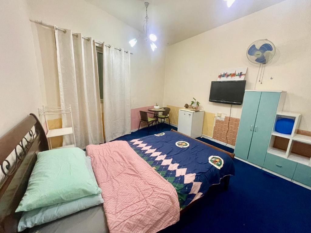 a bedroom with a bed and a flat screen tv at Salahuddin Metro Home Stay in Dubai