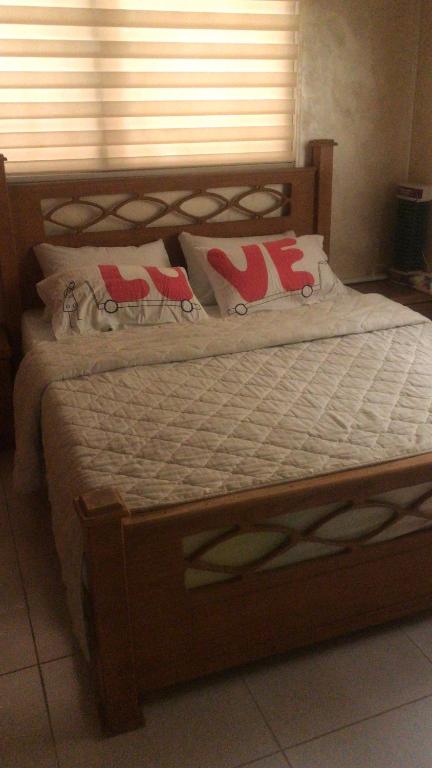 1 cama con marco de madera y almohadas en Taiky, en Um Qeis