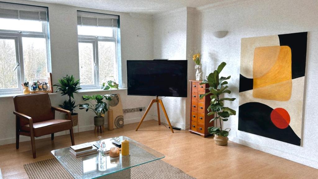 sala de estar con TV de pantalla plana y mesa en Spacious and Bright Apartment, en Londres