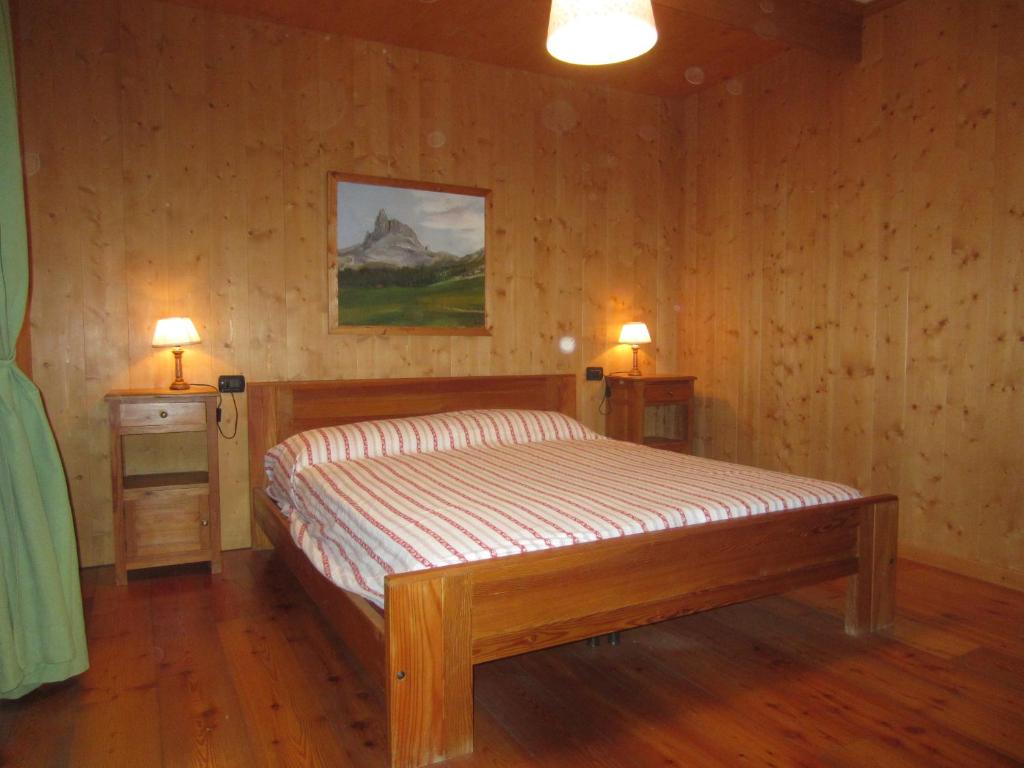 a bedroom with a bed and two lamps on two tables at Appartamento Serdes Big C2 in San Vito di Cadore