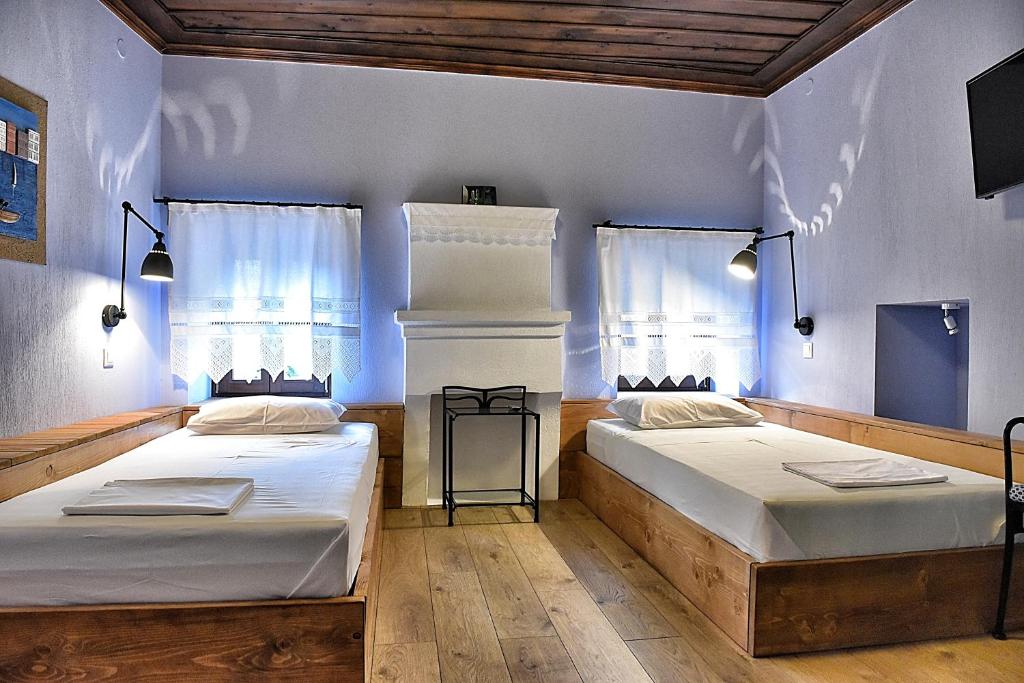 two beds in a room with two windows at Melina Hotel - Heritage in Poligiros