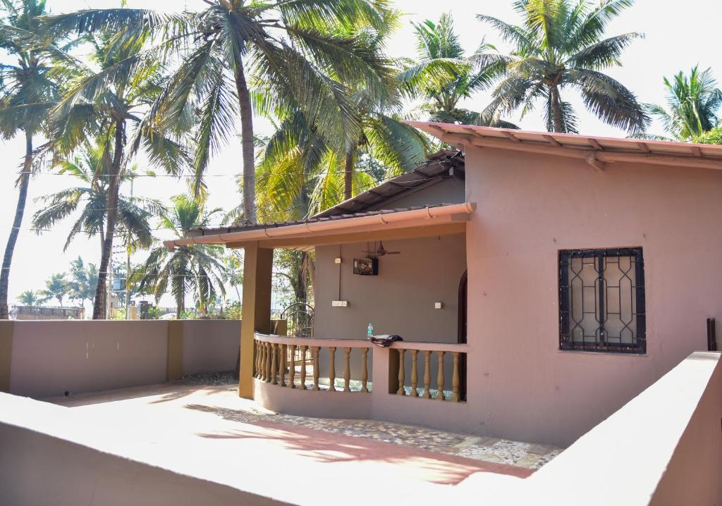 a house with palm trees in the background at Valerys Nest Bogmalo - Private villa near the beach and Dabolim airport in Bogmolo