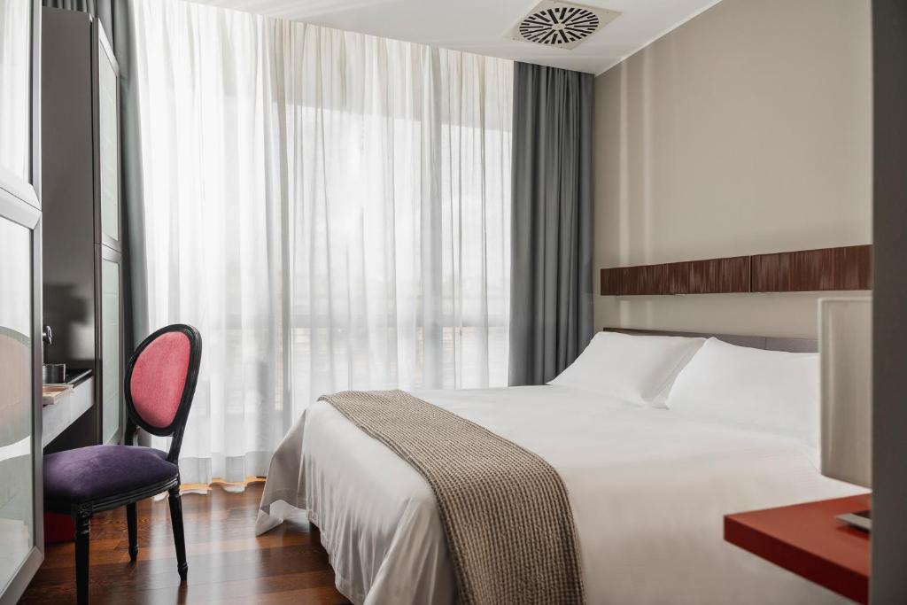 a bedroom with a bed and a chair and a window at Welcome Hotel in San Marino