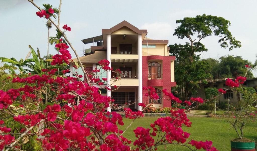 ein Haus mit rosa Blumen davor in der Unterkunft Bononi Guest House Jorhat in Jorhat