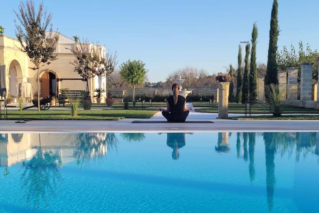 Eine Frau, die in einer Meditationsposition neben einem Pool sitzt. in der Unterkunft Villa Anna - Suites & Events in Specchia