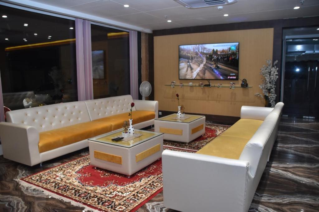 a living room with white furniture and a tv at Hotel Shivlok International By BookingCare in Satna