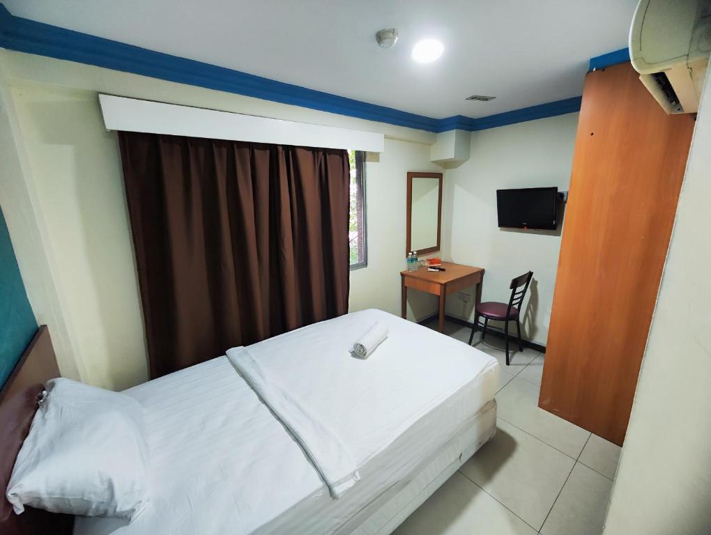 Schlafzimmer mit einem Bett und einem Schreibtisch mit einem TV in der Unterkunft Wings Grand Orchard Hotel in Kuala Lumpur