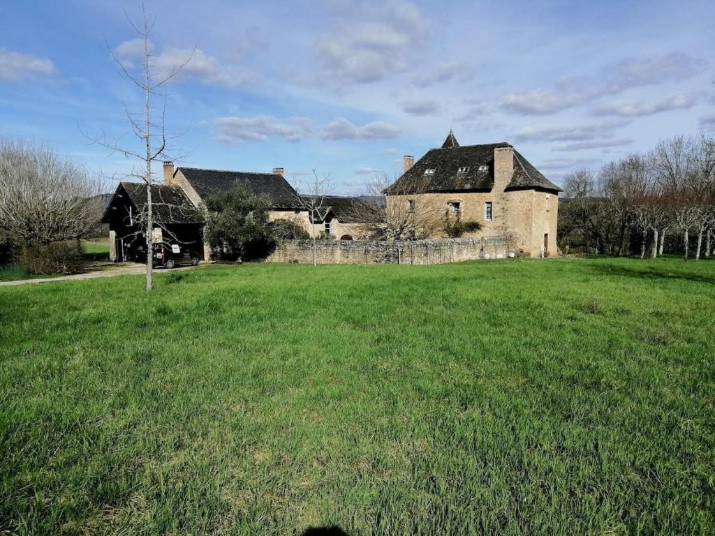 una vecchia casa in un campo con un campo verde di La Coudonie a Sarrazac