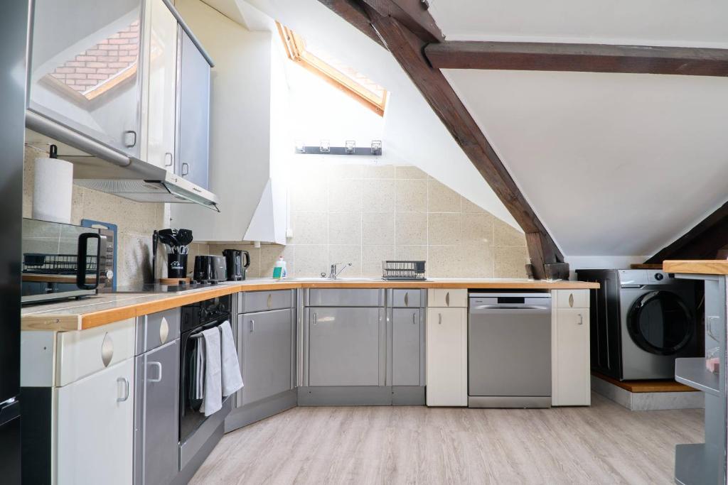 Il comprend une cuisine avec des placards blancs et un plafond voûté. dans l'établissement LE NID DE LA GLORIETTE Hyper centre NANTES, à Nantes