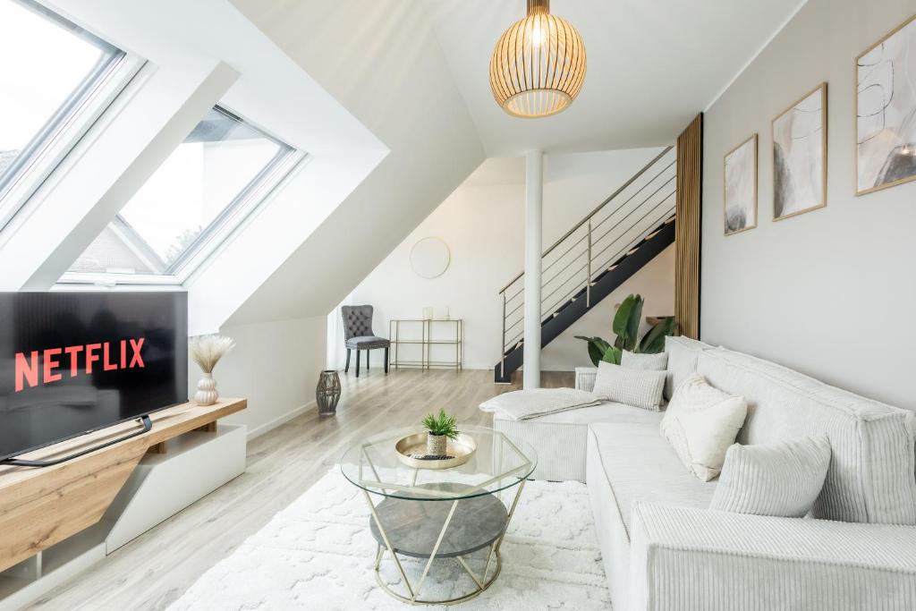 un soggiorno con divano bianco e TV di Gemütliche Penthouse-Wohnung I Jacuzzi I Gasgrill a Rheda-Wiedenbrück