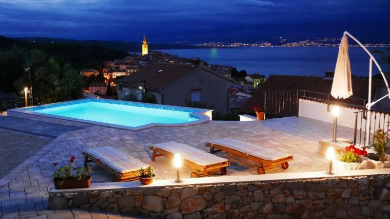 a swimming pool with benches and a view of the water at Apartment with private pool and beautiful sea view - by Traveler tourist agency Krk - ID 2106 in Vrbnik