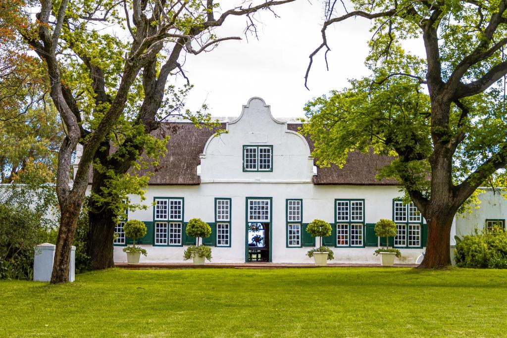 an exterior view of a white house with trees at Hawksmoor House in Stellenbosch