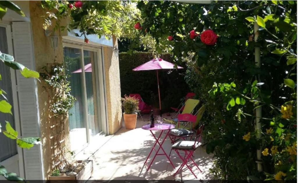 eine Terrasse mit 2 Stühlen und einem Sonnenschirm in der Unterkunft Le Temps Des Cerises. in Vinsobres