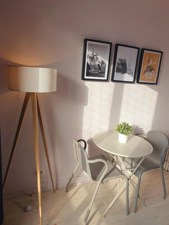 a table and chairs in a room with a lamp at Vue sur Paris in Ivry-sur-Seine